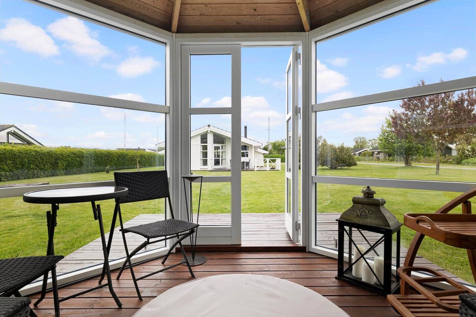 Terrasse mit Tisch, Stühlen und Blick auf grünen Garten und Haus.