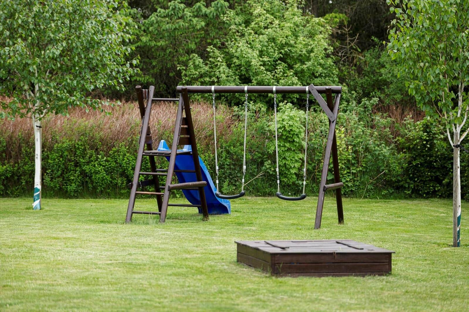 Hinterhof mit Holzschaukel, blauer Rutsche und Spielplatzfläche.