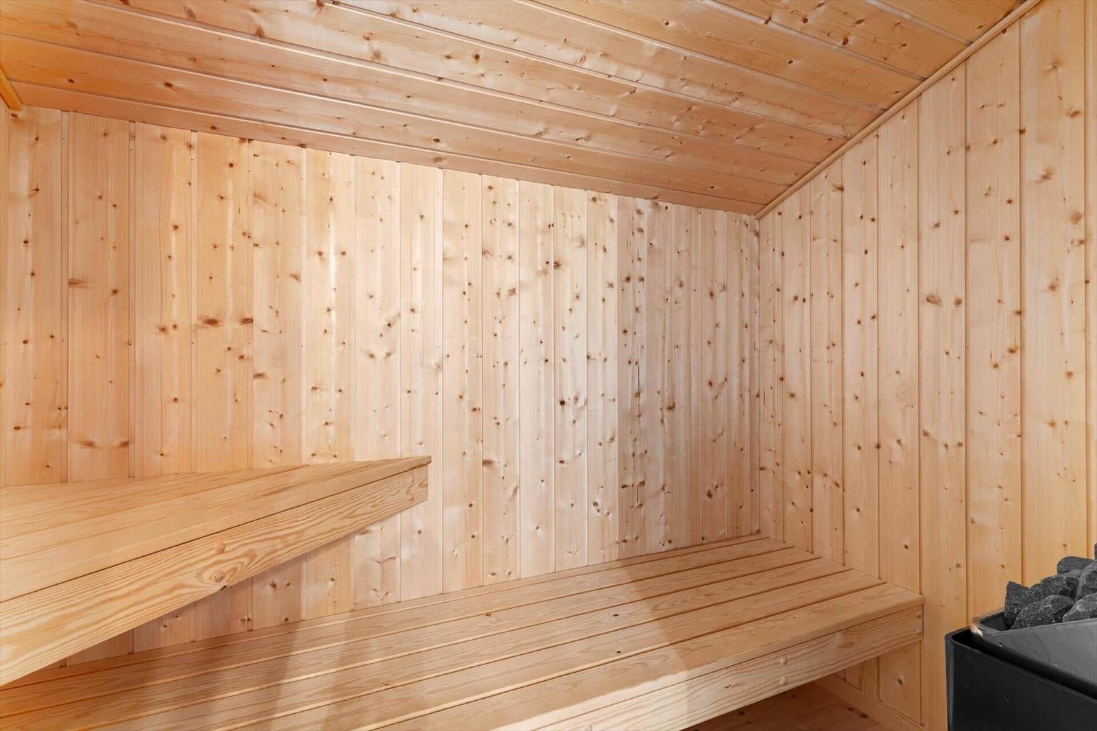 Holzsauna mit Banken und Steinmulde.