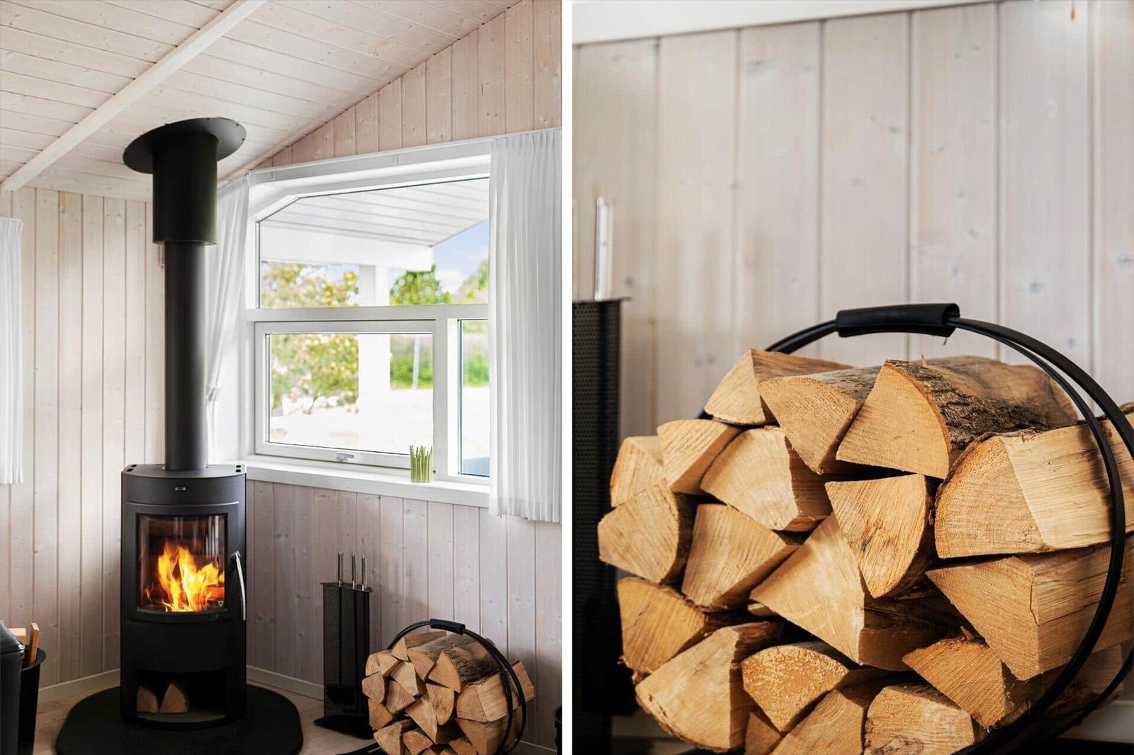 Kaminofen mit Holzstapel in rustikalem Raum mit Holzwand und Fenster.