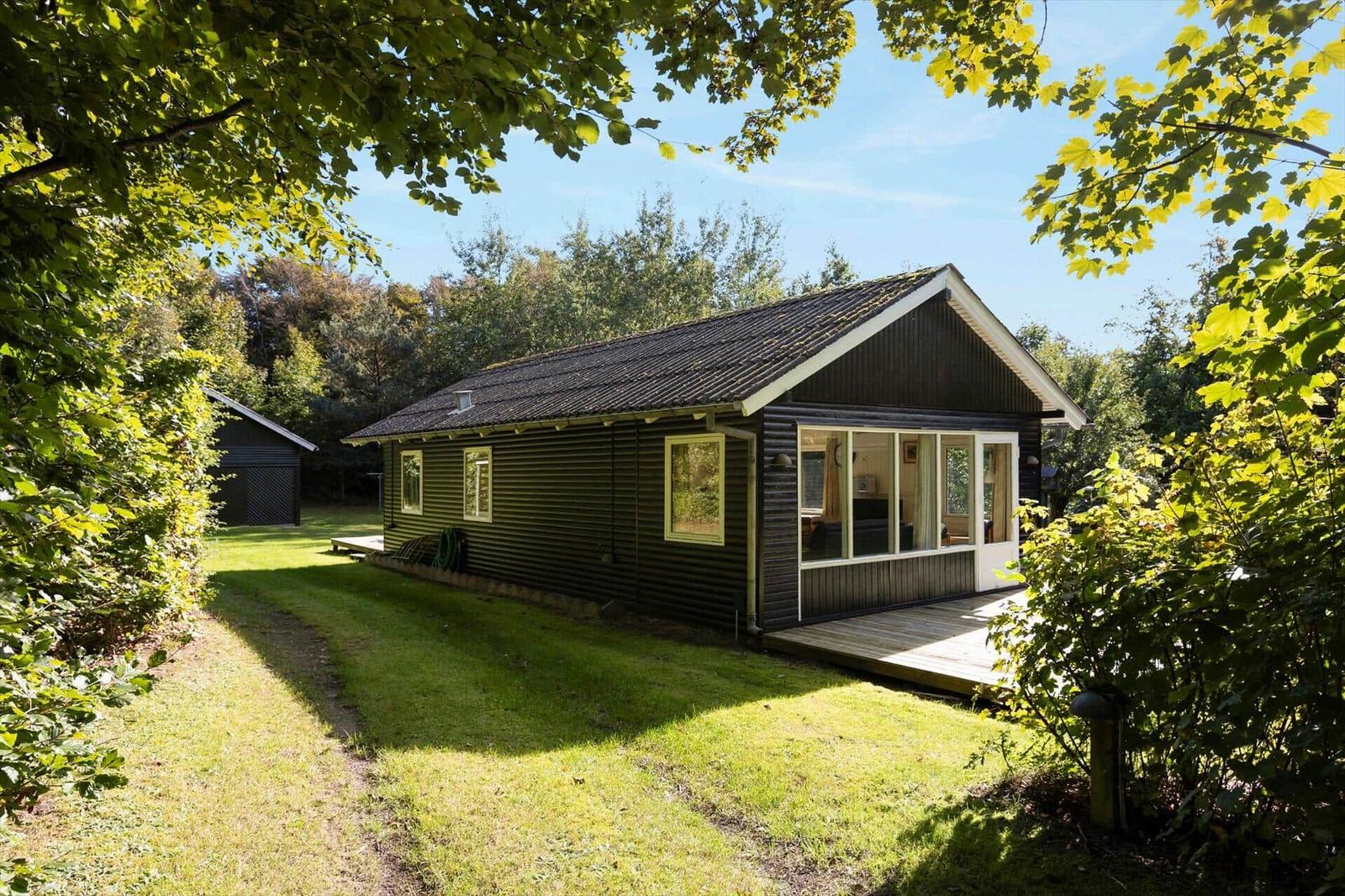 Ein kleines Haus mit Holzfassade und Terrasse im Grünen.