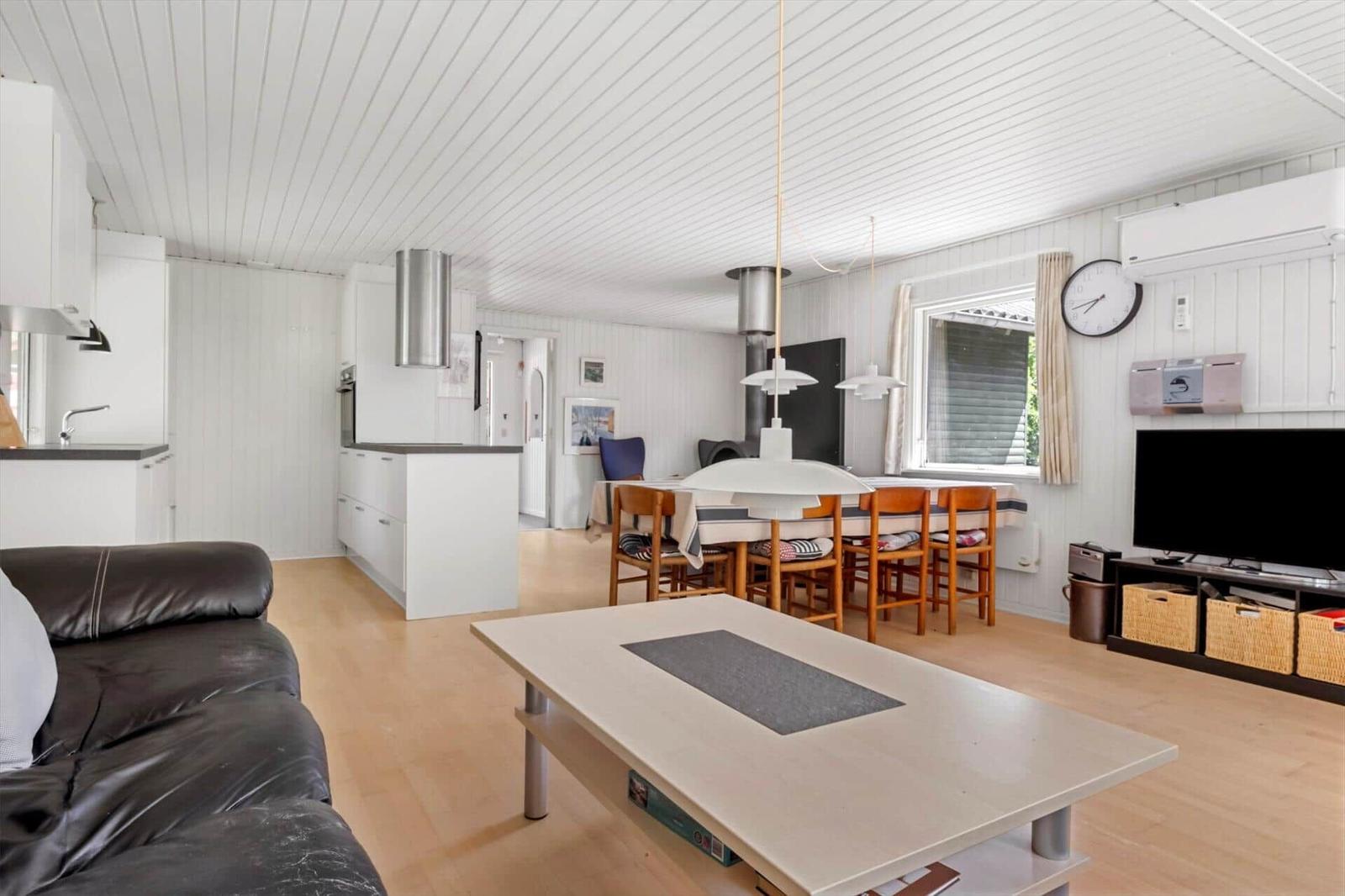 Wohn-Essbereich mit Küche, Sofa, Esstisch und Fernseher.