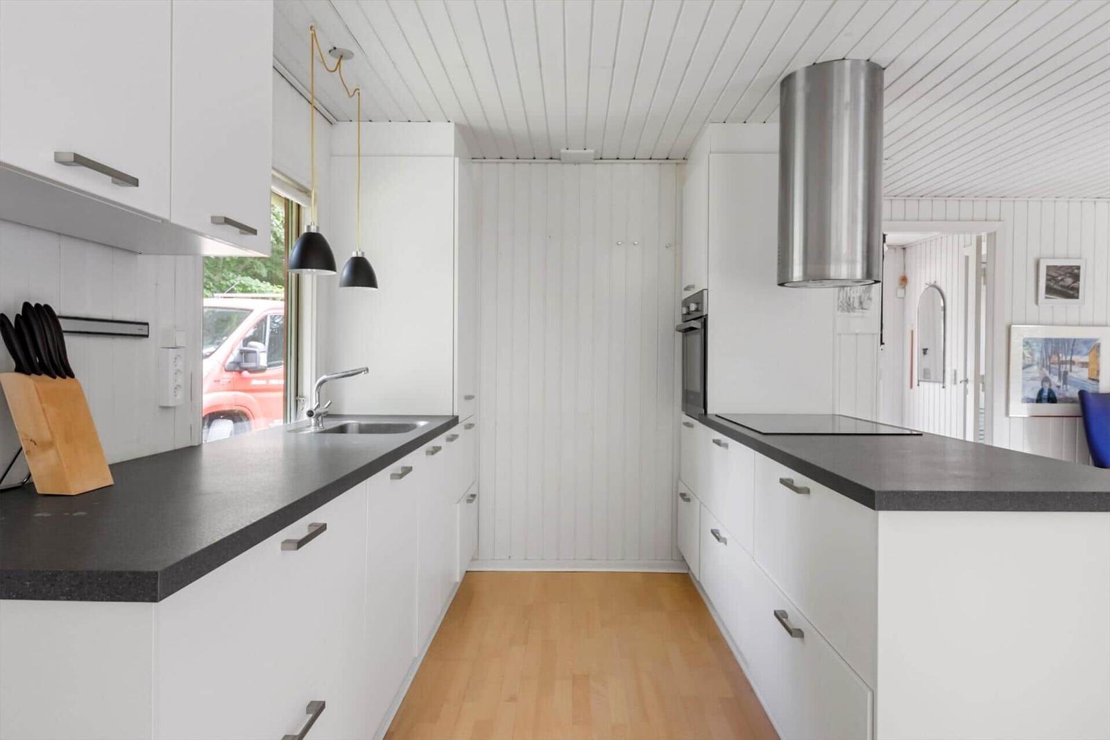 Moderne Küche mit weißen Schränken, dunkler Arbeitsplatte und Holzboden.