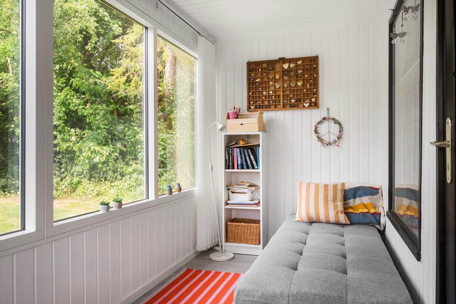 Raum mit großem Fenster, Sofa, Bücherregal und Wanddekoration.