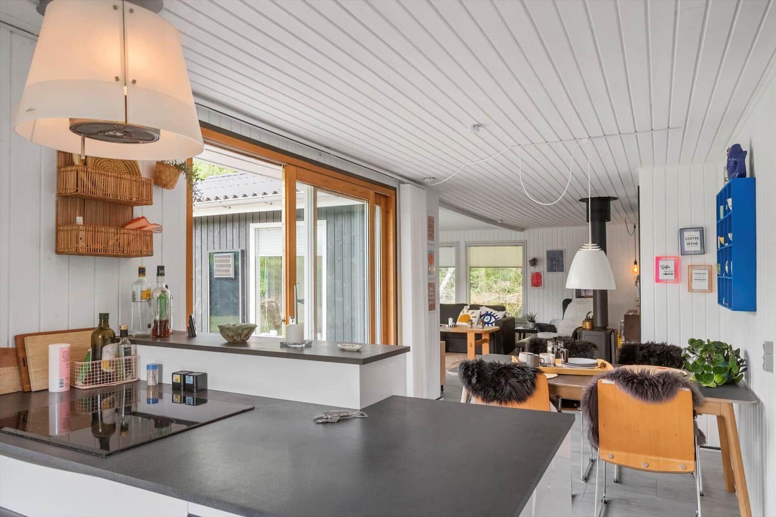 Küche mit Essbereich, Holzmöbel und Glasfront zur Außenterrasse.