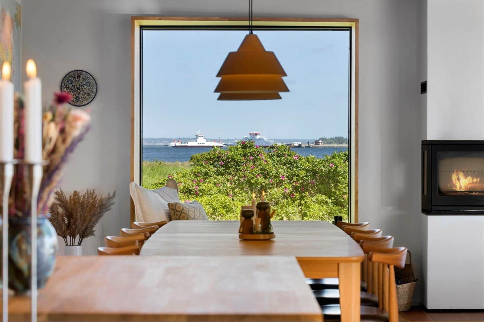 Dining room with sea and ship view. Wooden table, chairs, fireplace, and window.