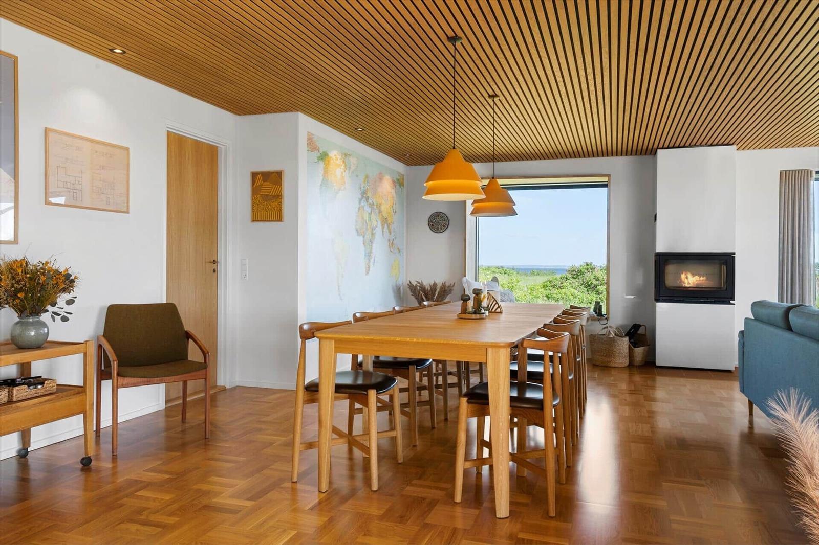 Dining room with wooden table, chairs, and view of the landscape.