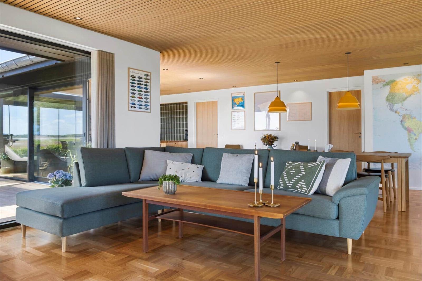 Living room with sofa, table, and wooden floor. Passage to terrace with view.