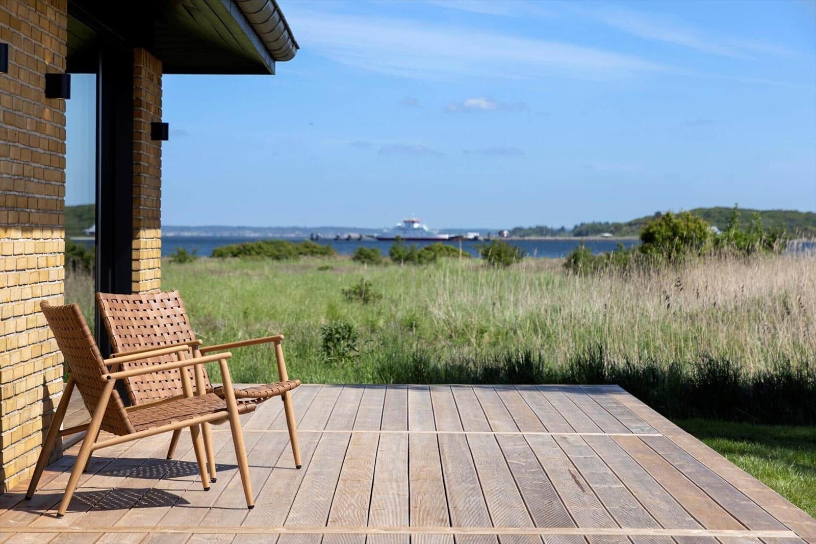 Deck with two chairs, view of water and grassland.