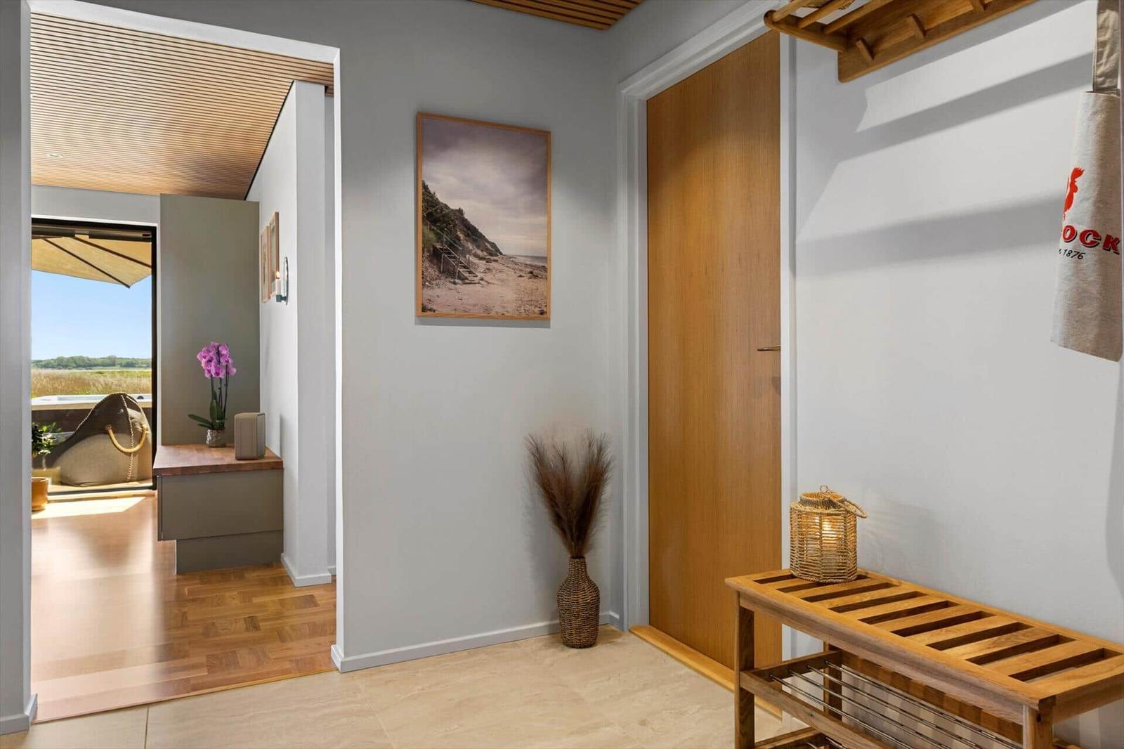 Entrance area with wooden door, wall art, and welcome bench with lamp.
