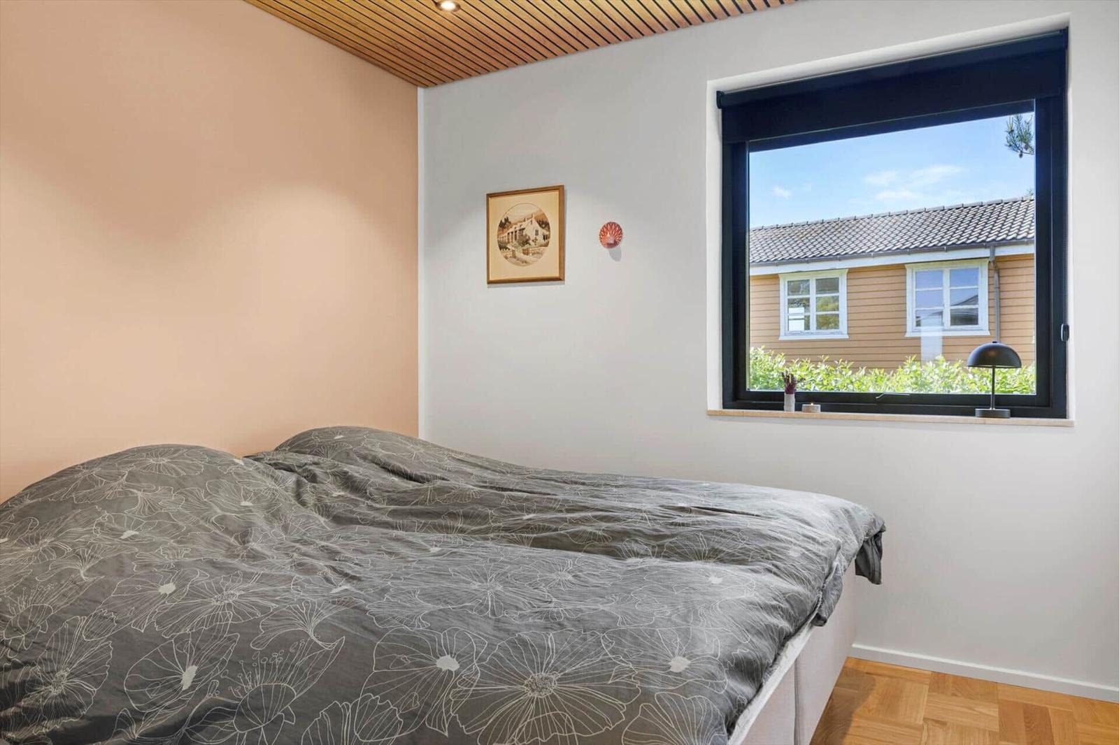 Bedroom with bed, window, and wooden ceiling. View of neighboring house.