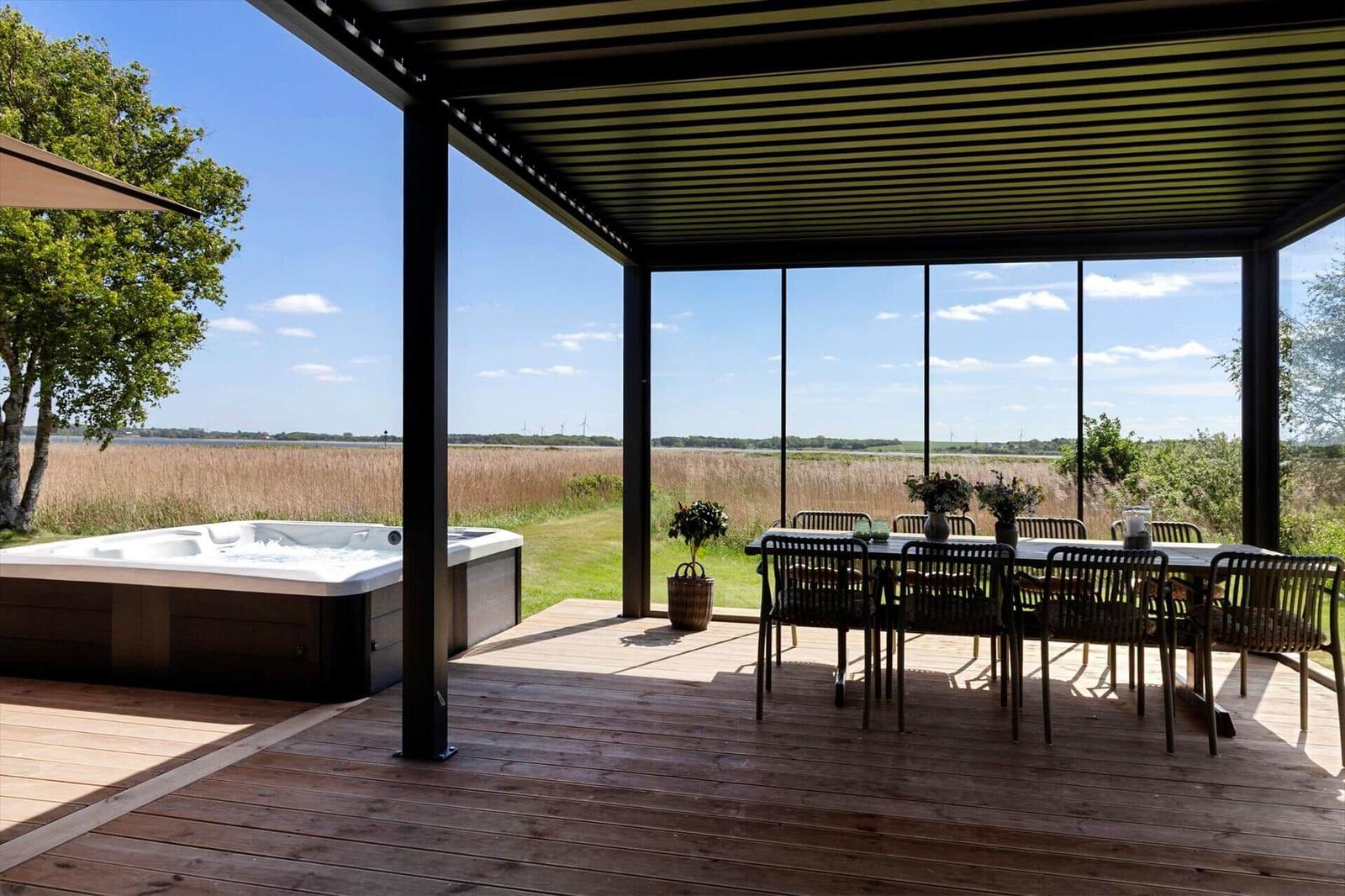 Deck with hot tub and dining area, view of field and sky.