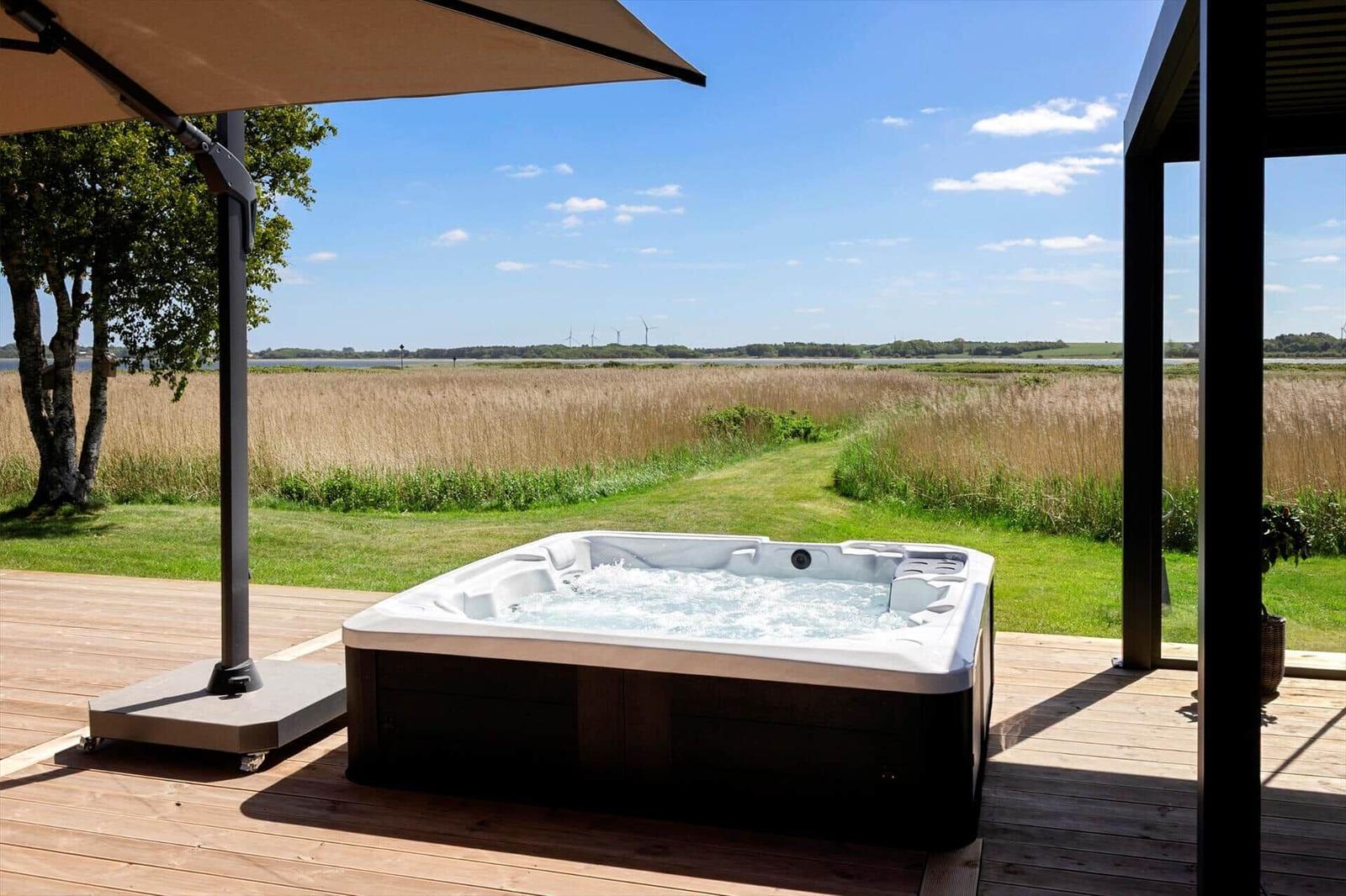 High-quality hot tub on terrace with view of field and water.
