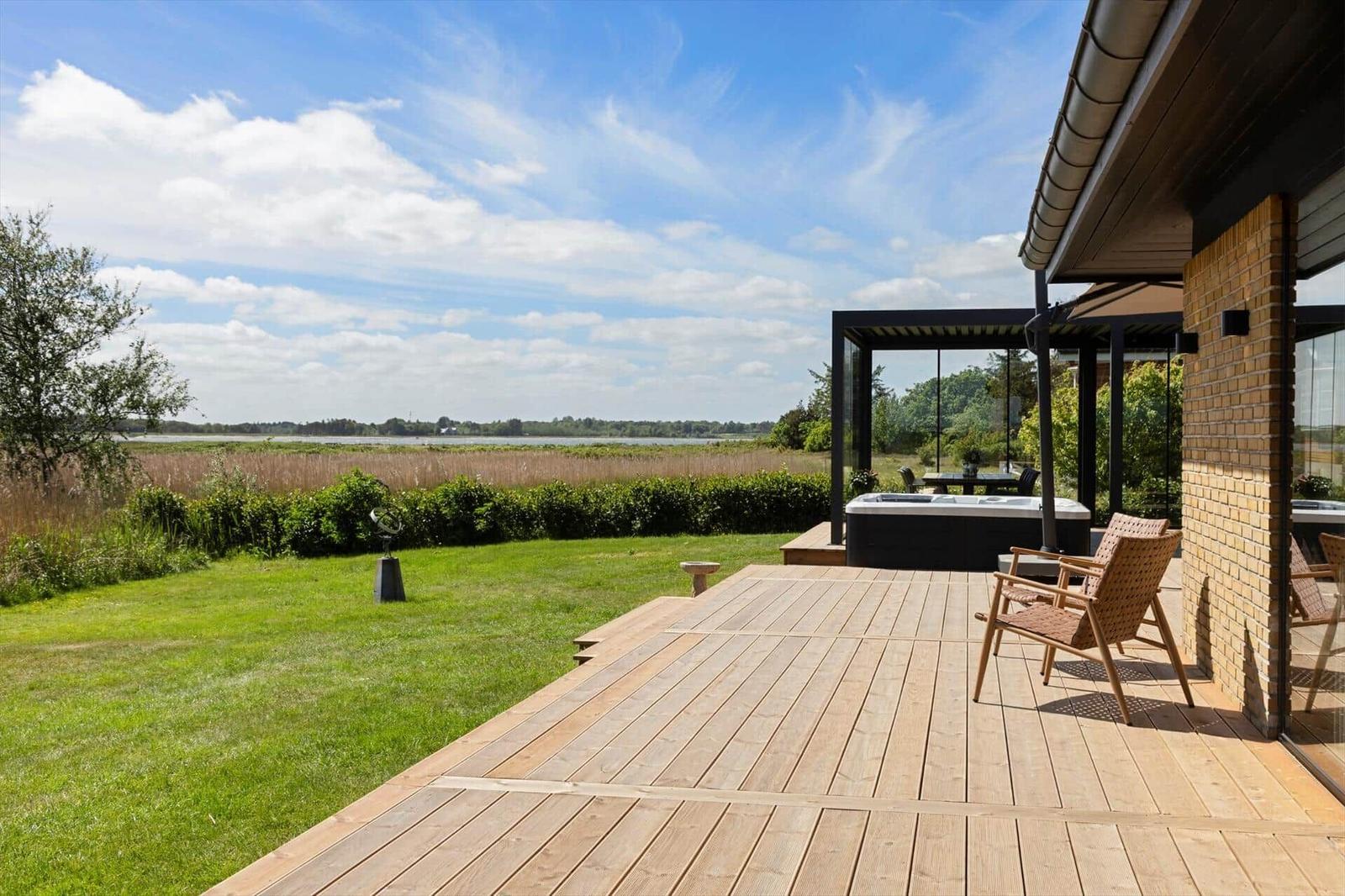Deck with hot tub and garden view of a lake.