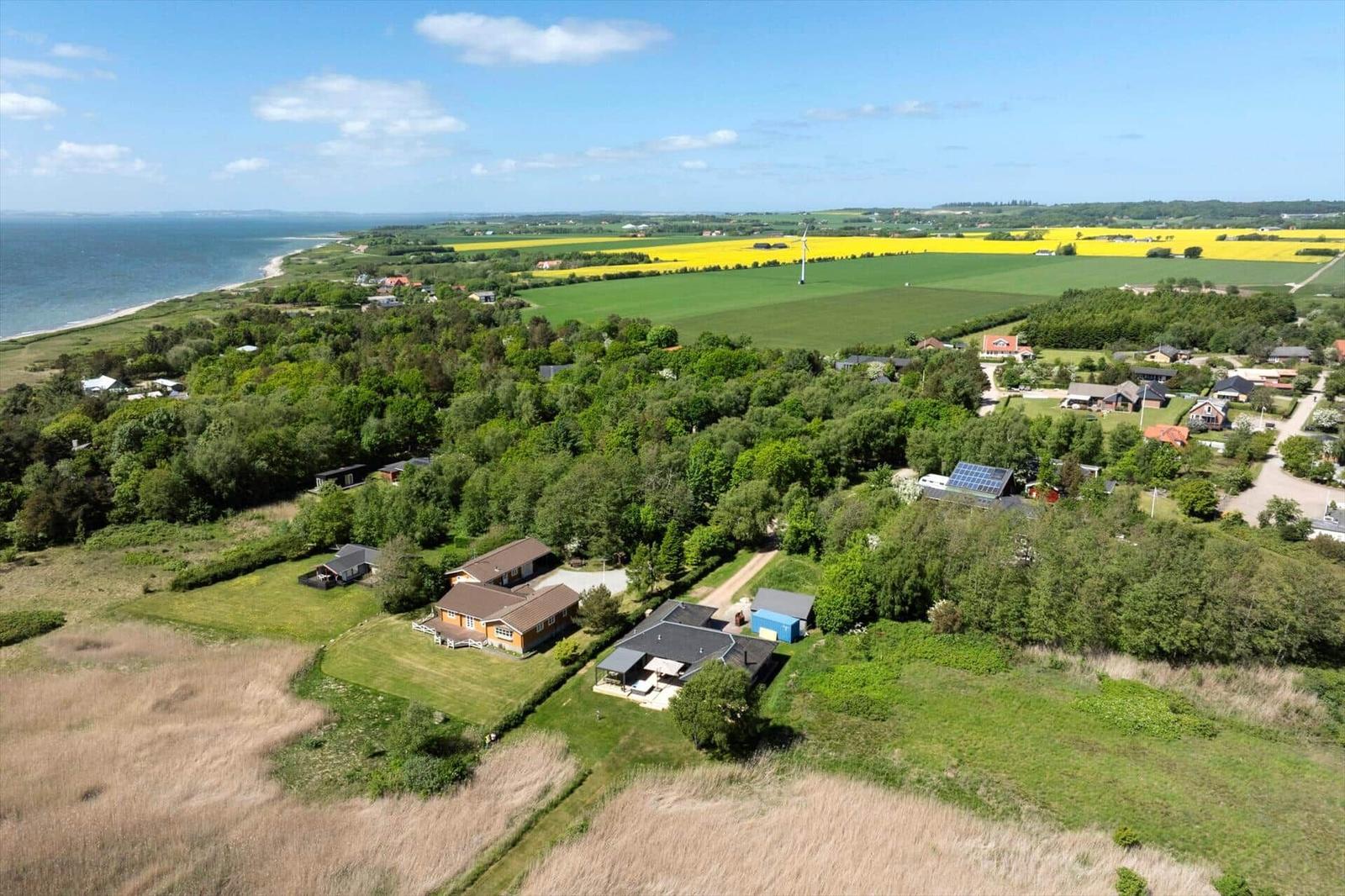 House with garden, surrounded by meadows and forest, view of sea and solar panels.