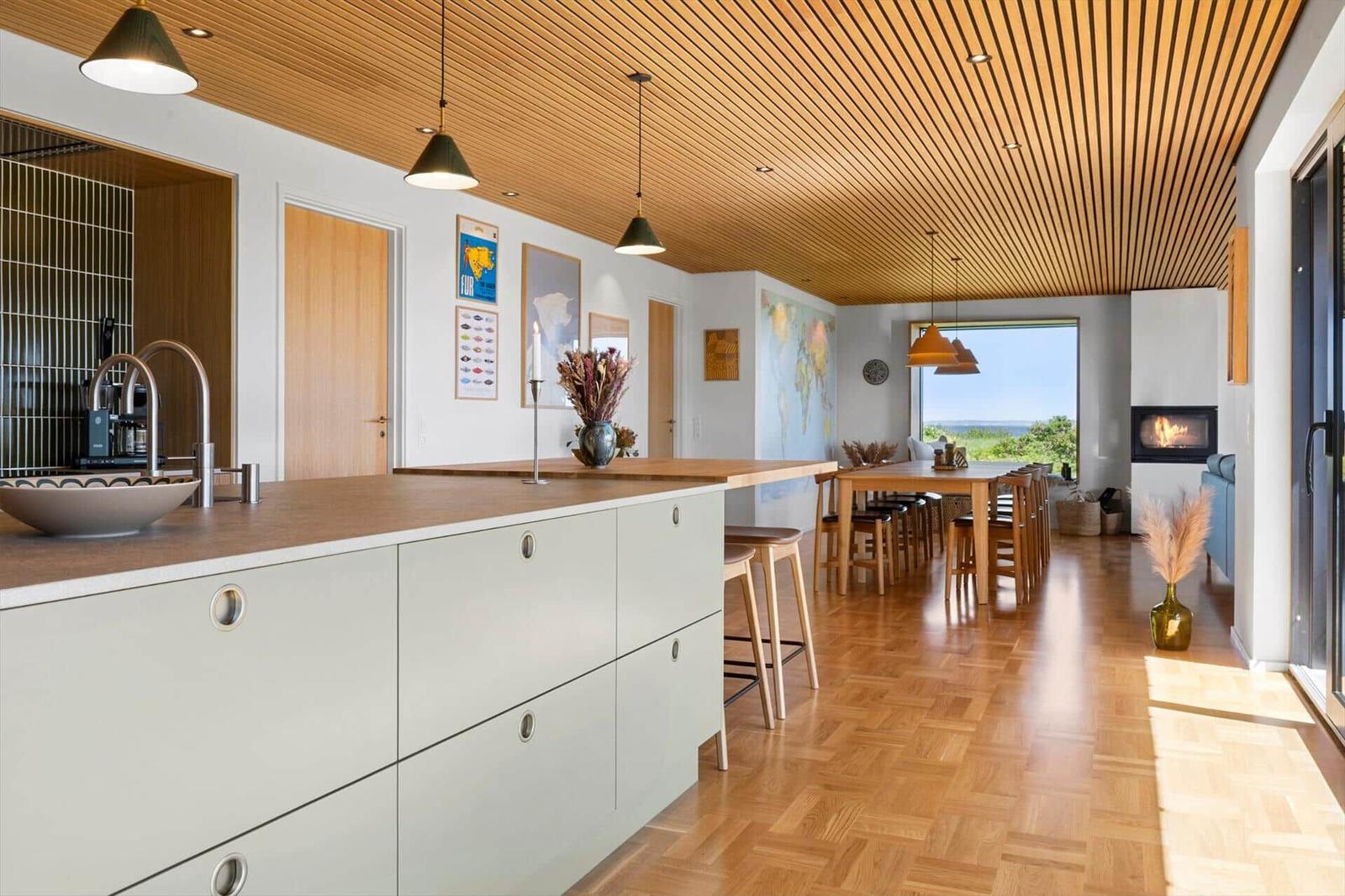 Kitchen with dining area and wooden ceiling. View of the sea. Fireplace and wooden floor.