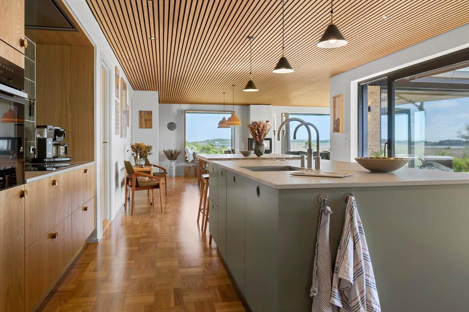 Modern kitchen with wooden ceiling and view of the landscape.