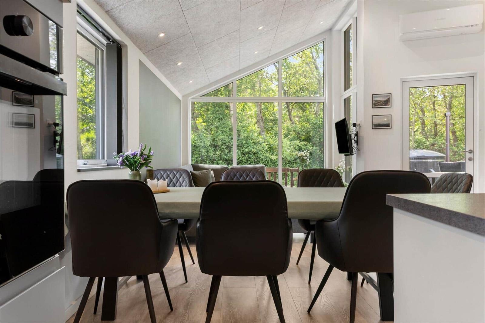 Essbereich mit Tisch und Stühlen, große Fenster zur grünen Umgebung