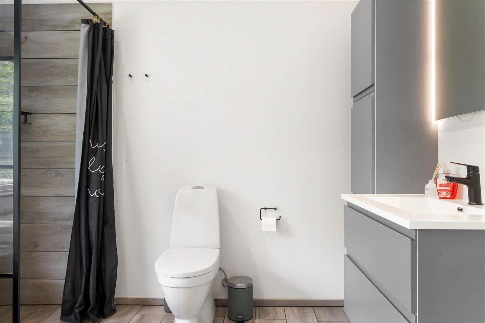 Badezimmer mit Toilette, Waschbecken und Dusche mit Vorhang.