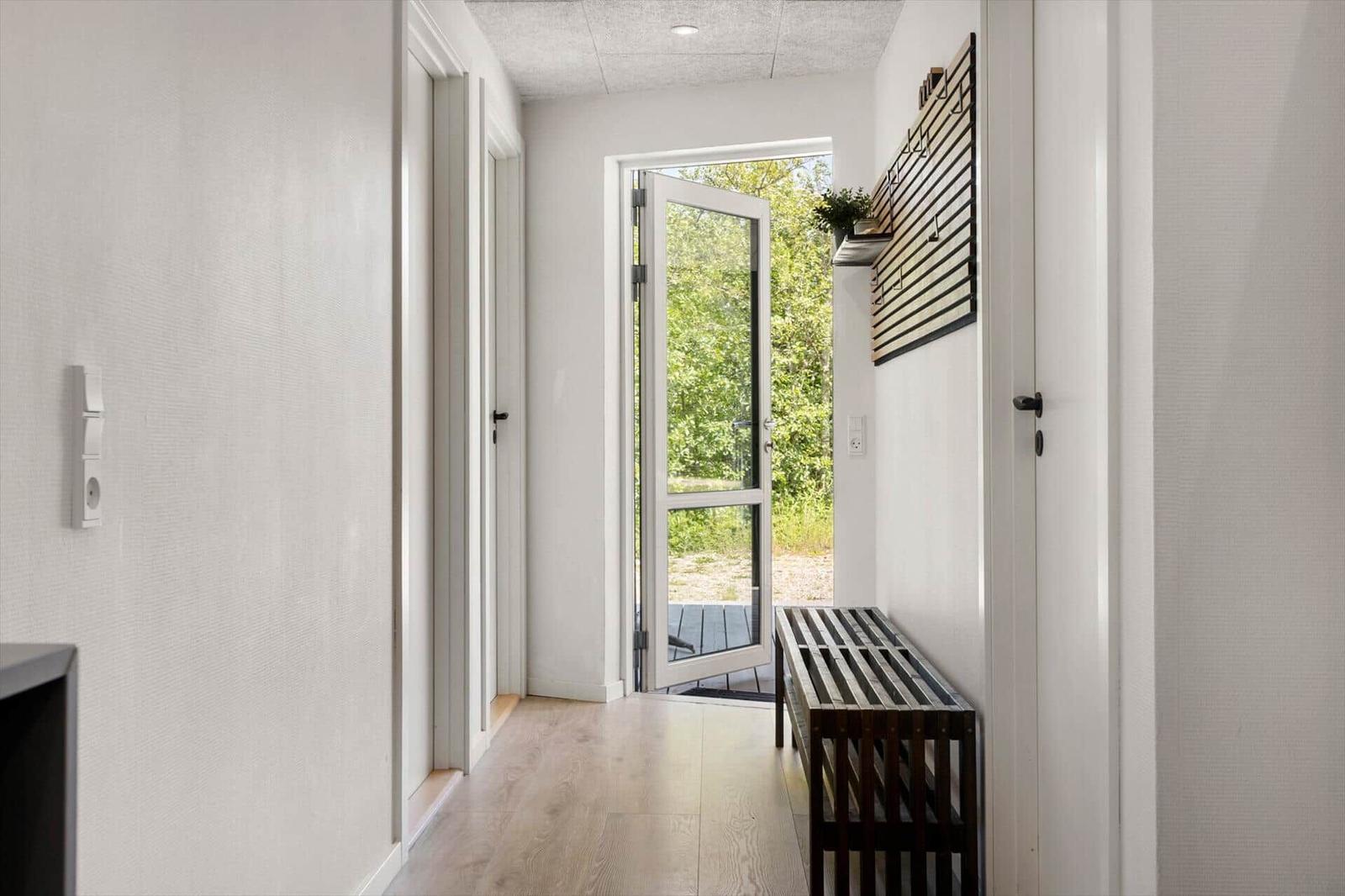 Hallenflur mit Holzboden, Sitzbank und Glastür zum Außenbereich.