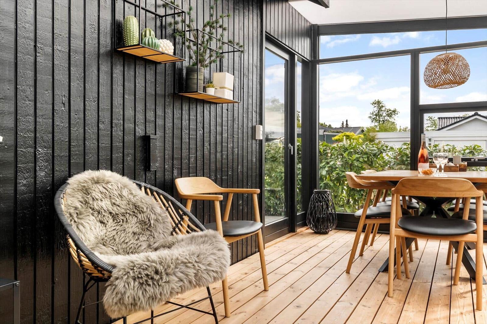 Terrasse mit Holzboden, Sitzgelegenheiten und Blick auf Grünflächen.