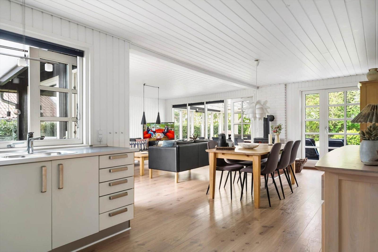 Küche, Essbereich und Wohnzimmer mit Holzboden und weißen Wänden.