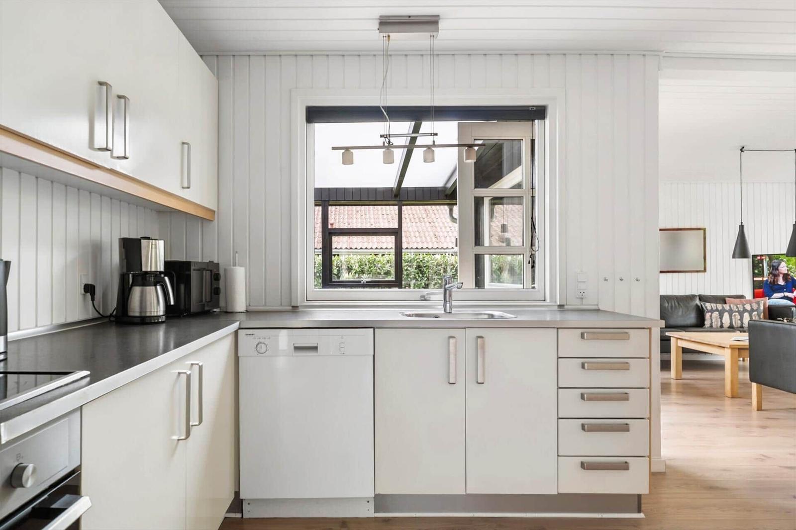 Küche mit Waschmaschine, Arbeitsplatte und Fenster zum Garten.
