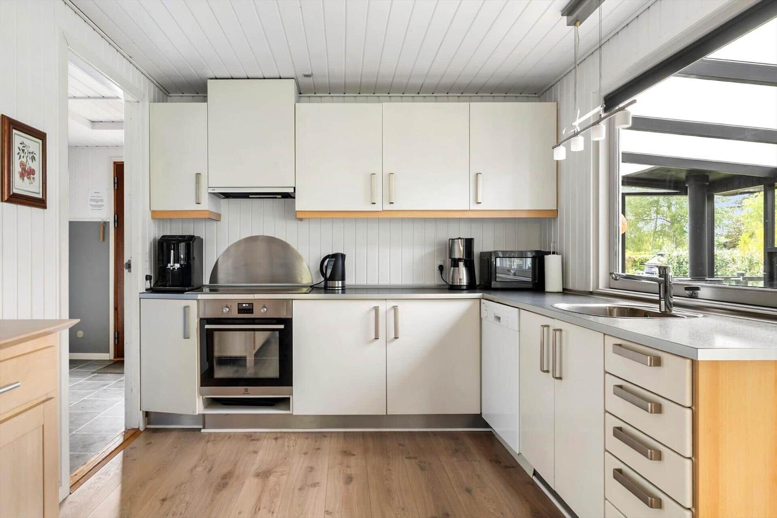 Moderne Küche mit weißen Schränken, Edelstahlgeräten und Holzboden.
