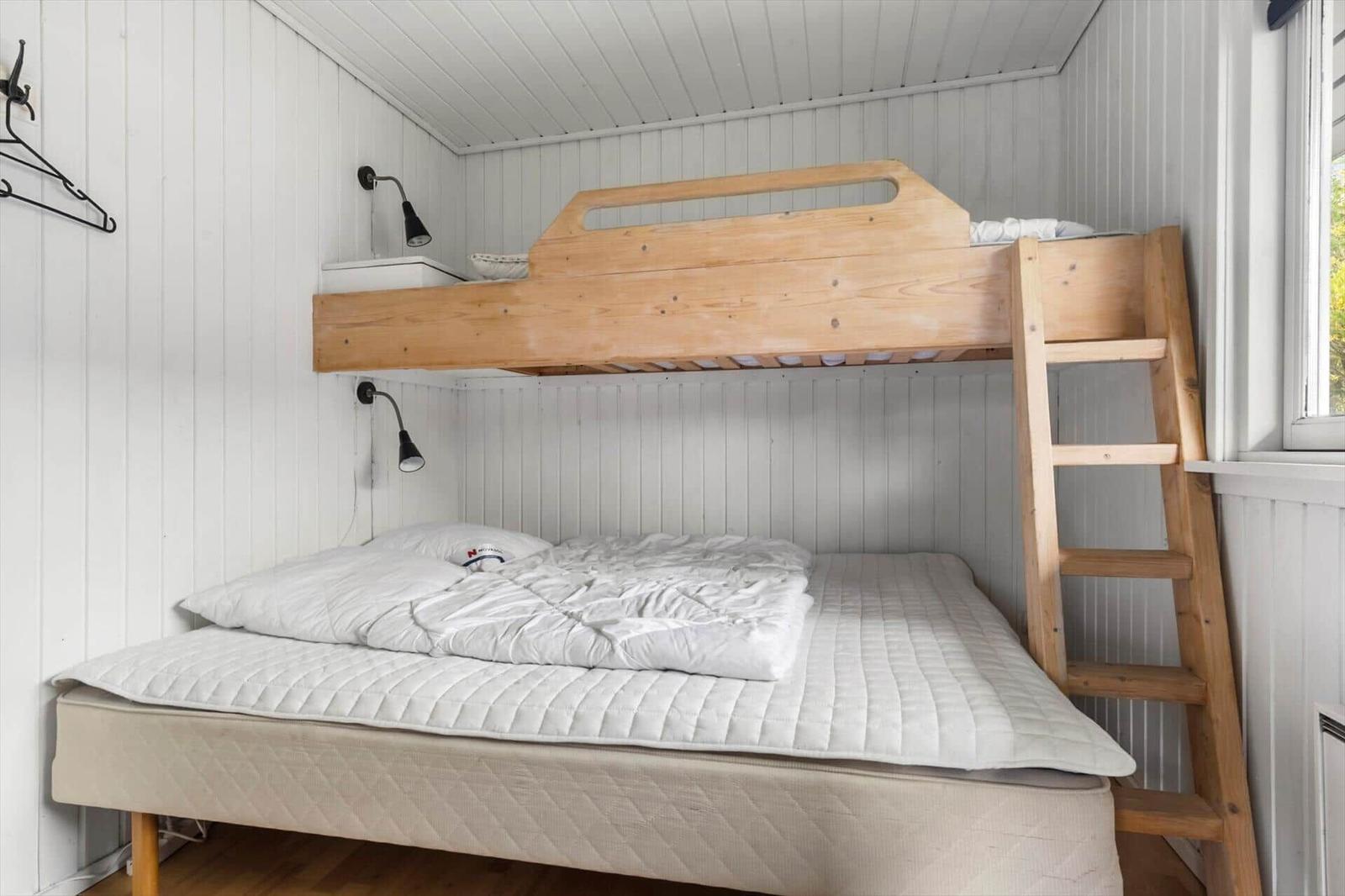 Hochbett mit Leiter und Matratze. Weiße Wände und Decke. Fenster rechts.