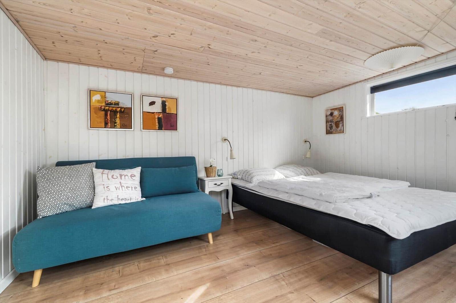 Ein Schlafzimmer mit Sofa, Bett und Wandbildern.