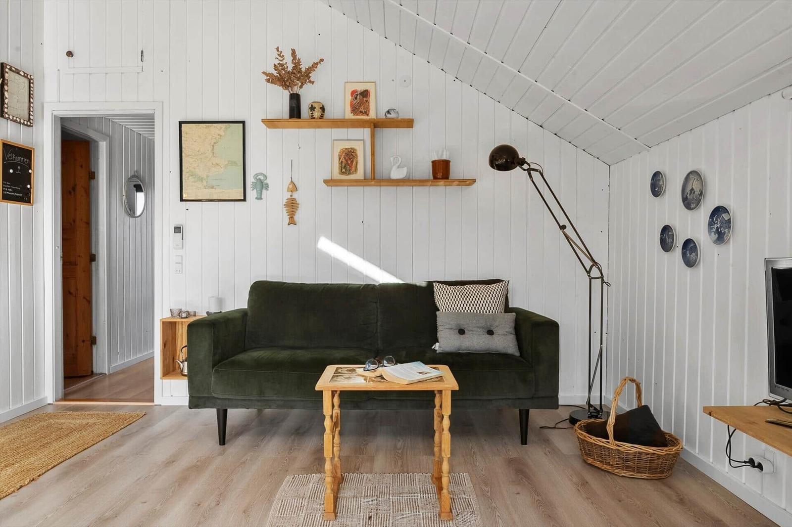 Ein Wohnzimmer mit grünem Sofa, Holztisch und weißen Wänden.