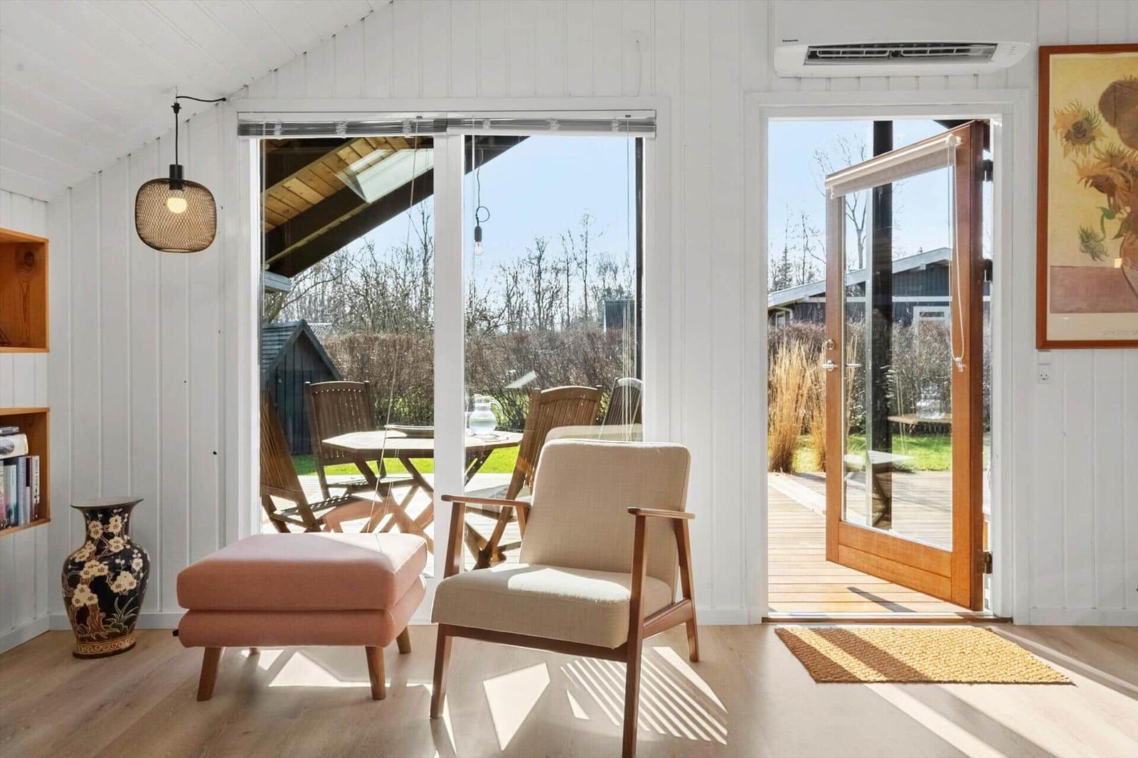 Wohnraum mit Sitzgelegenheit, Schiebetür und Blick auf Terrasse und Garten.