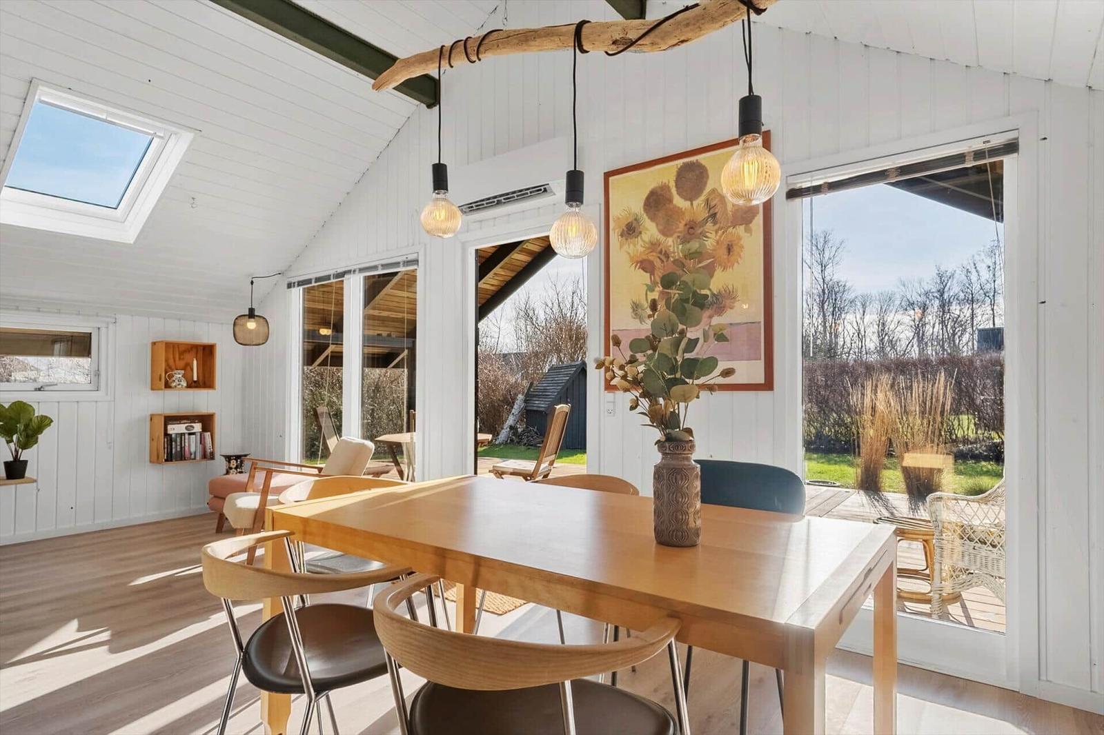 Esszimmer mit Holztisch, Stühlen und Blick auf den Garten.