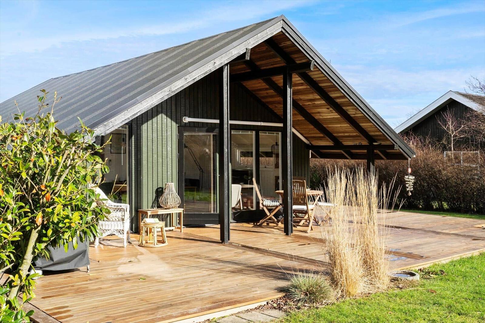 Moderne Villa mit Holzterrasse und großem Sitzbereich unter Dach.