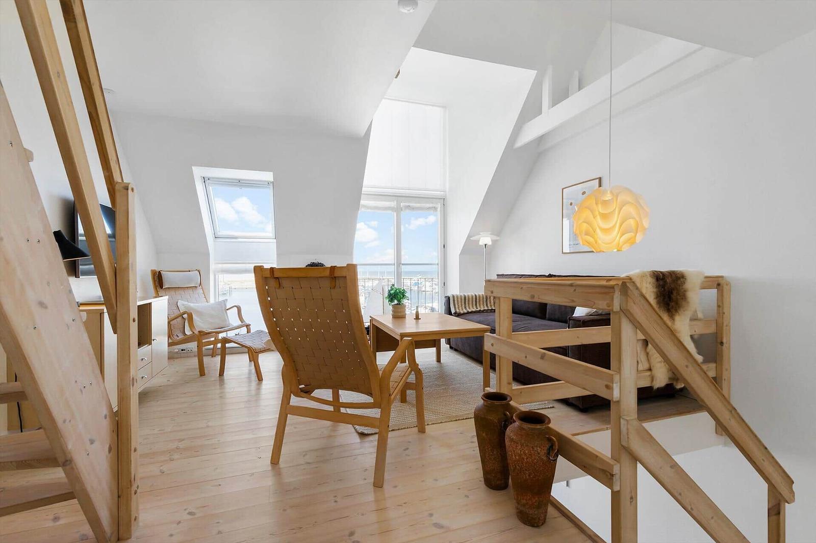 Living space with wooden floor, seating, and sea view.
