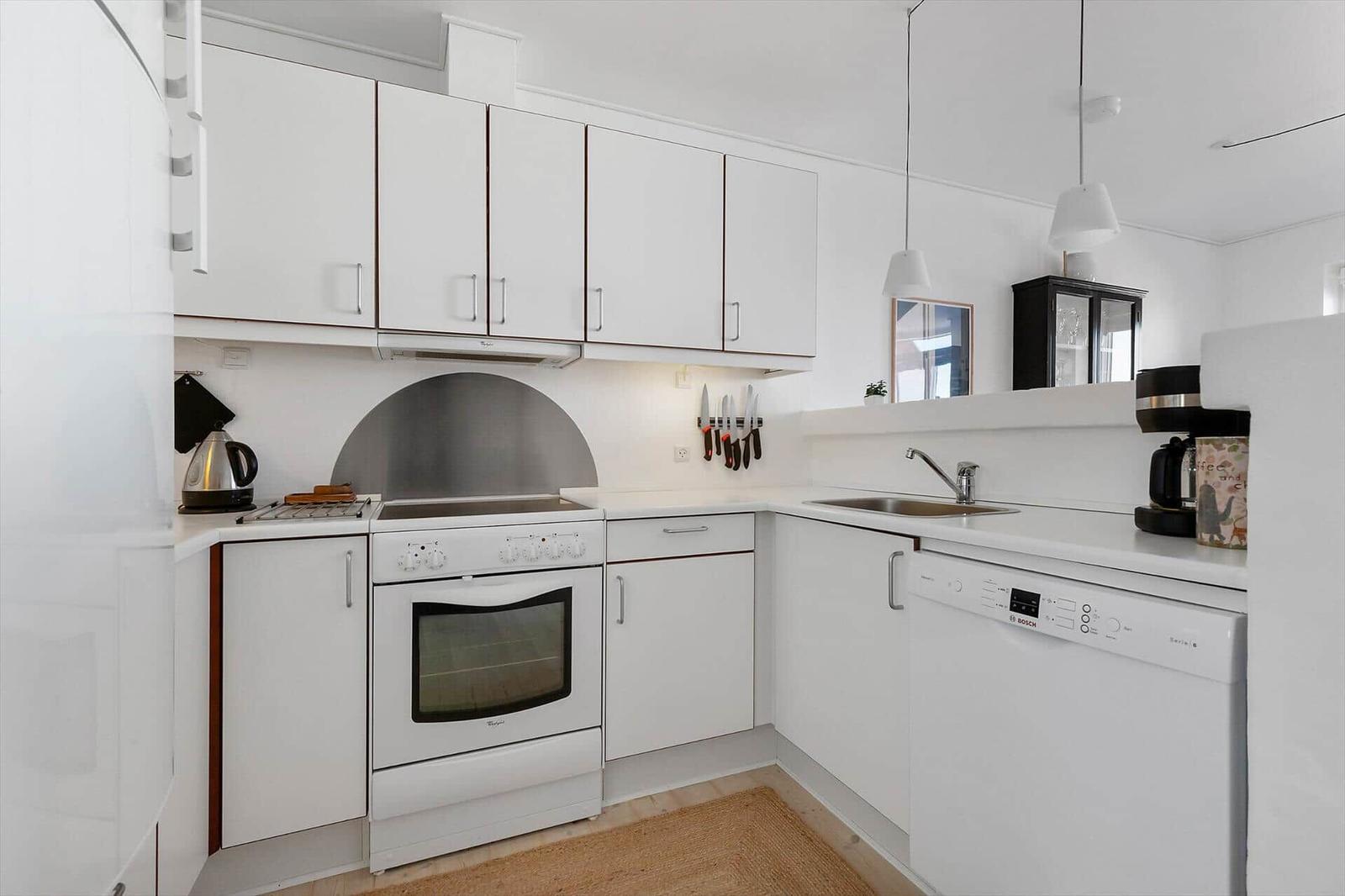 Kitchen with white cabinets, stove, sink, and dishwasher.
