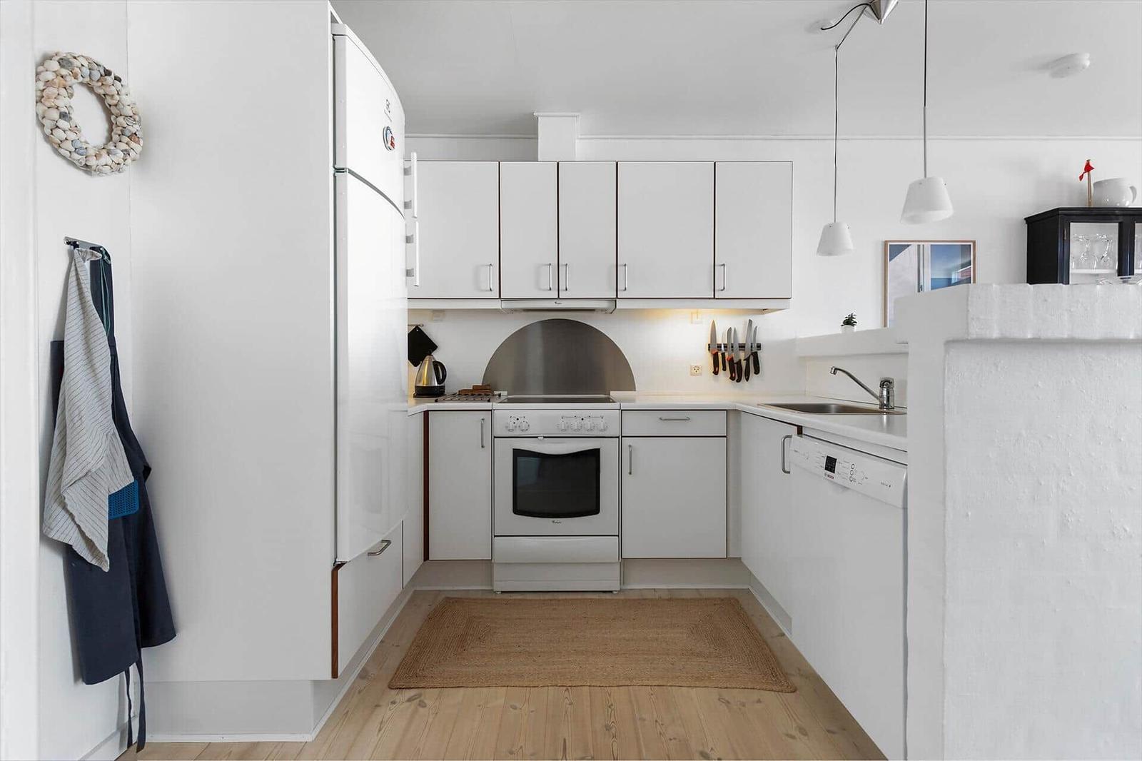 Kitchen with white cabinets, refrigerator, stove, and sink.