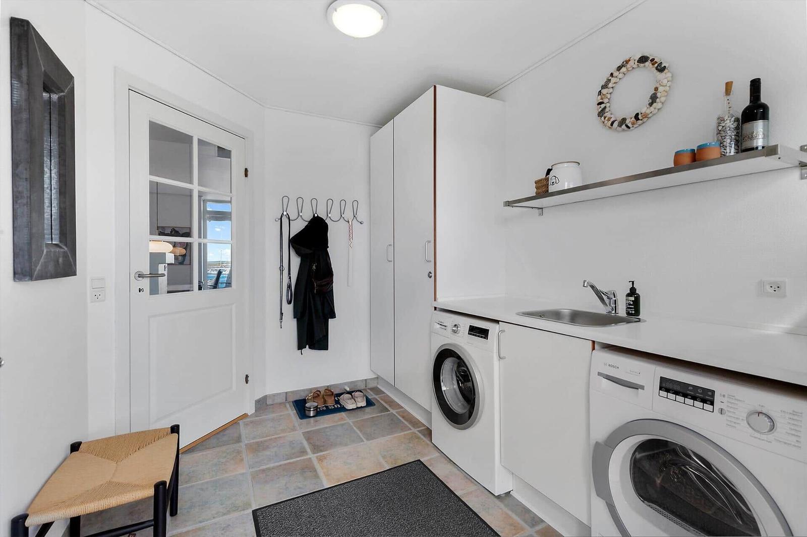 Entrance with washing machine, sink, and coat hooks. Door with glass panes.