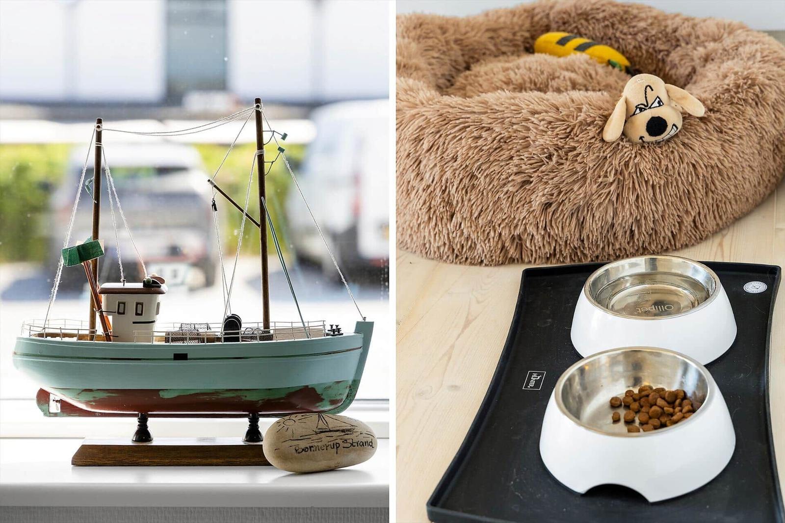 A model boat sits on a windowsill. A dog bed with food bowls is on the floor.