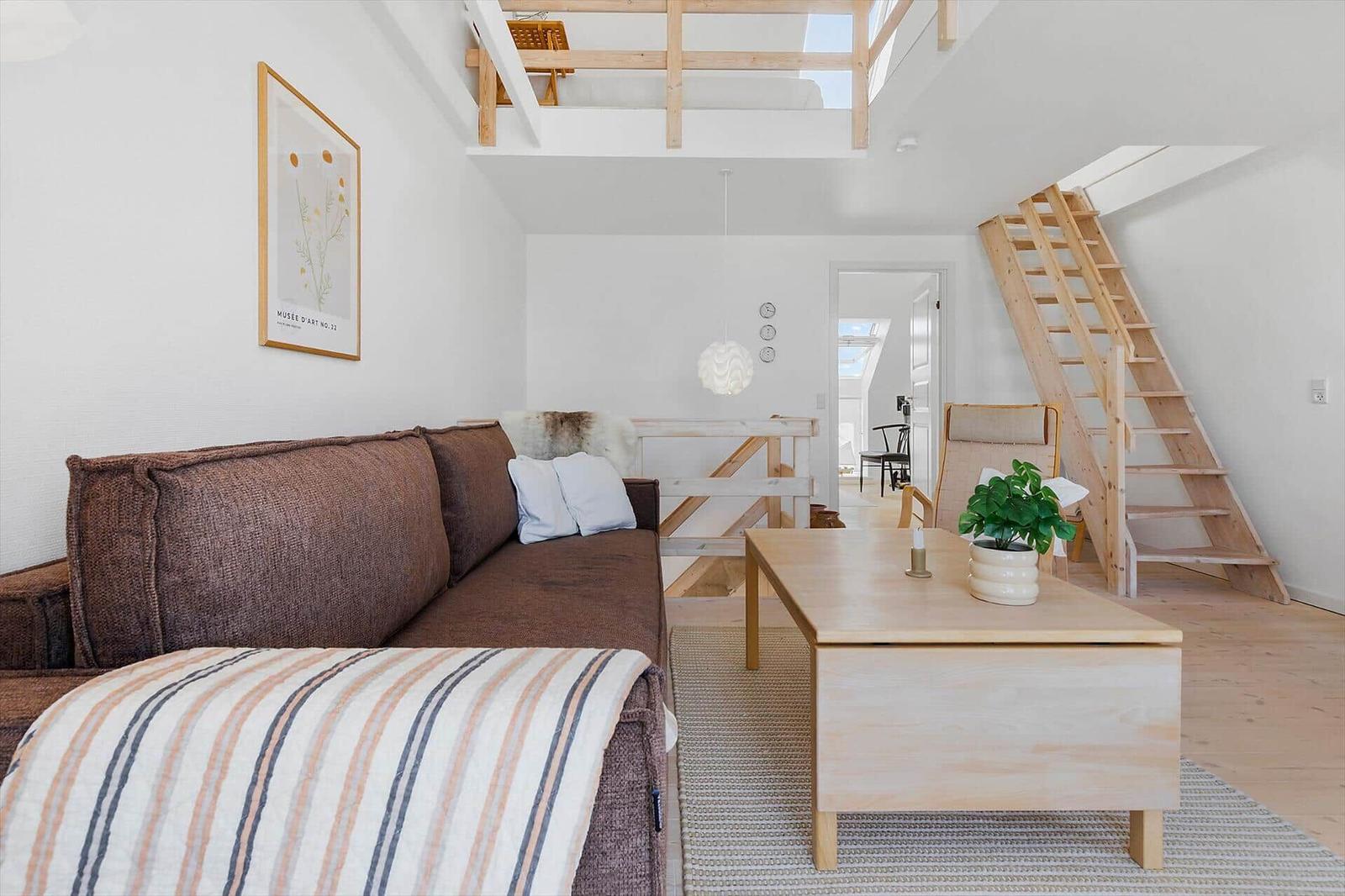 Living room with brown sofa, wooden table, and staircase to upper level.