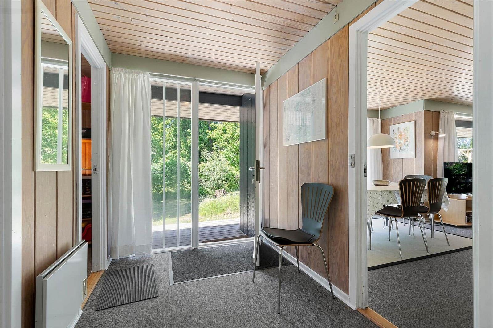 Entrance with chair, sliding door, view into dining room.