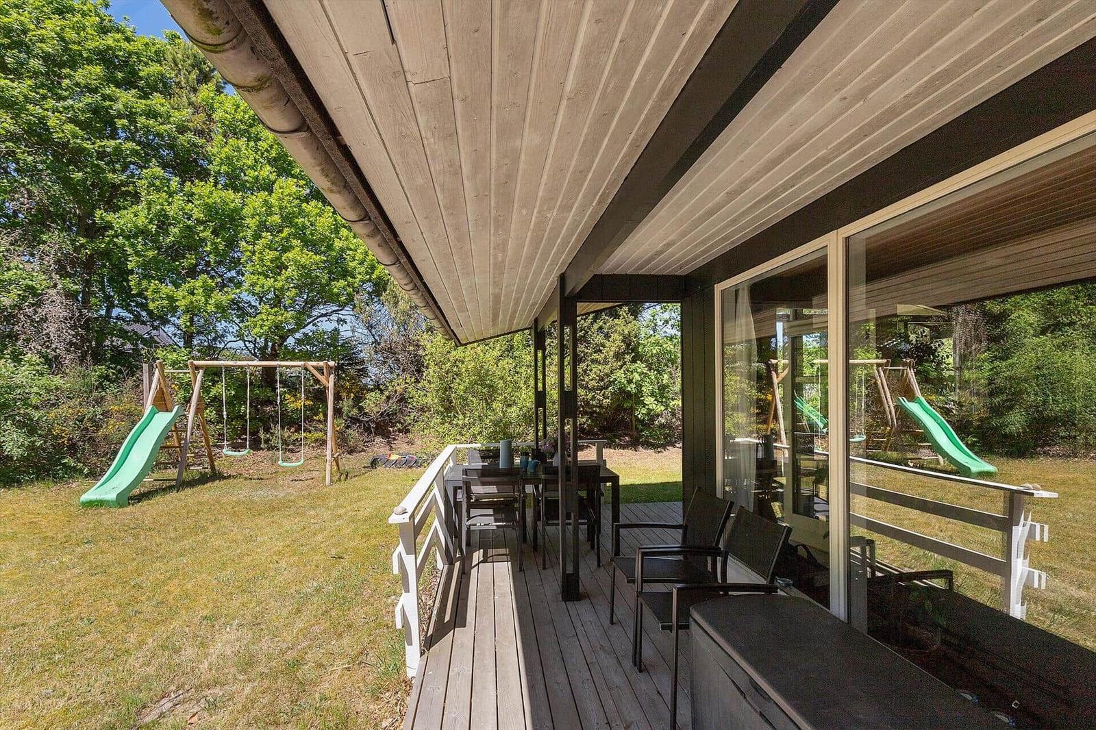 Deck with seating and view of a playground with slide.
