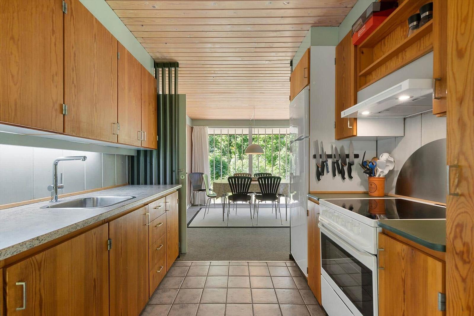 Kitchen with wooden cabinets and view into dining area with table and chairs.