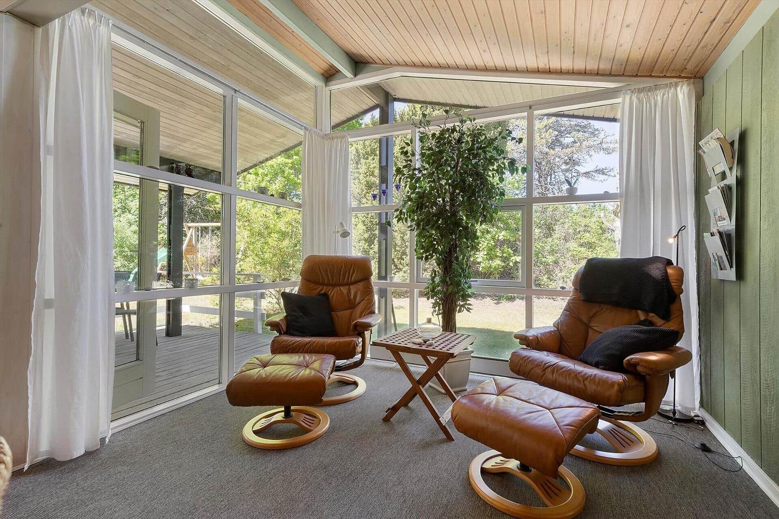 Two brown recliners with footstools and a table are by large windows.