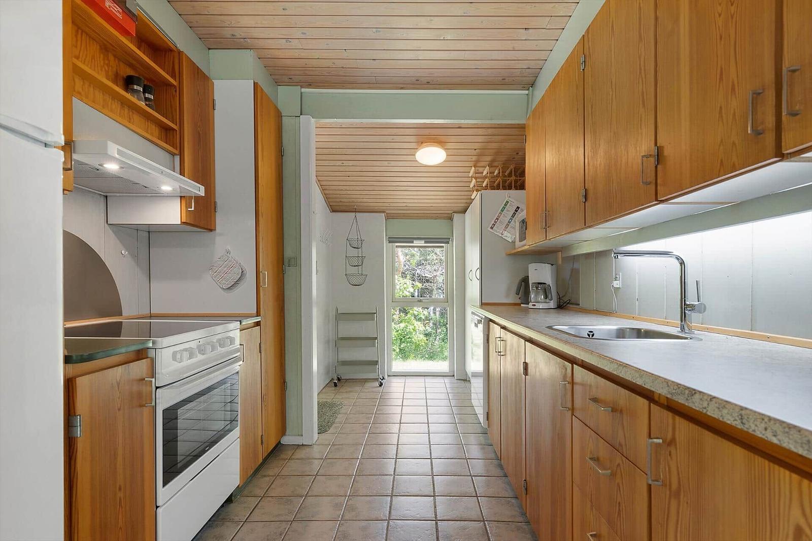 Kitchen with wooden cabinets, stone countertop, and window to the garden.