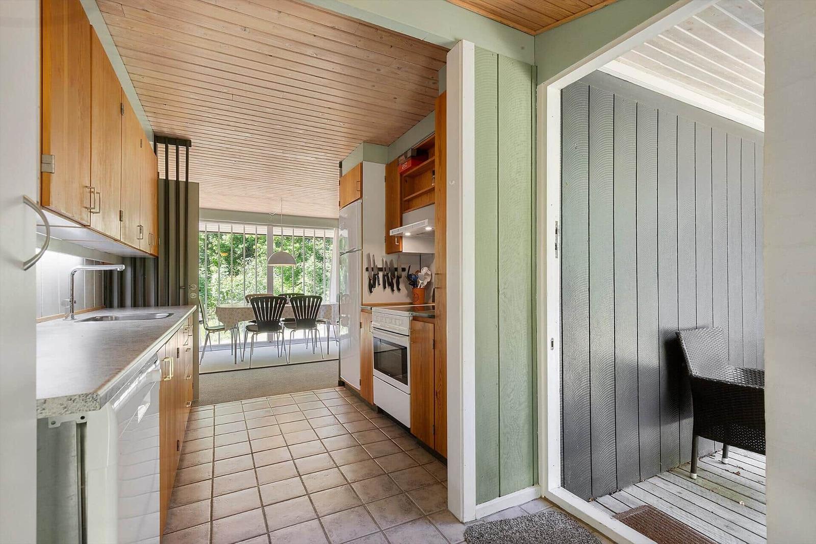 Kitchen with wooden cabinets, countertop, and view of dining area with table and chairs.