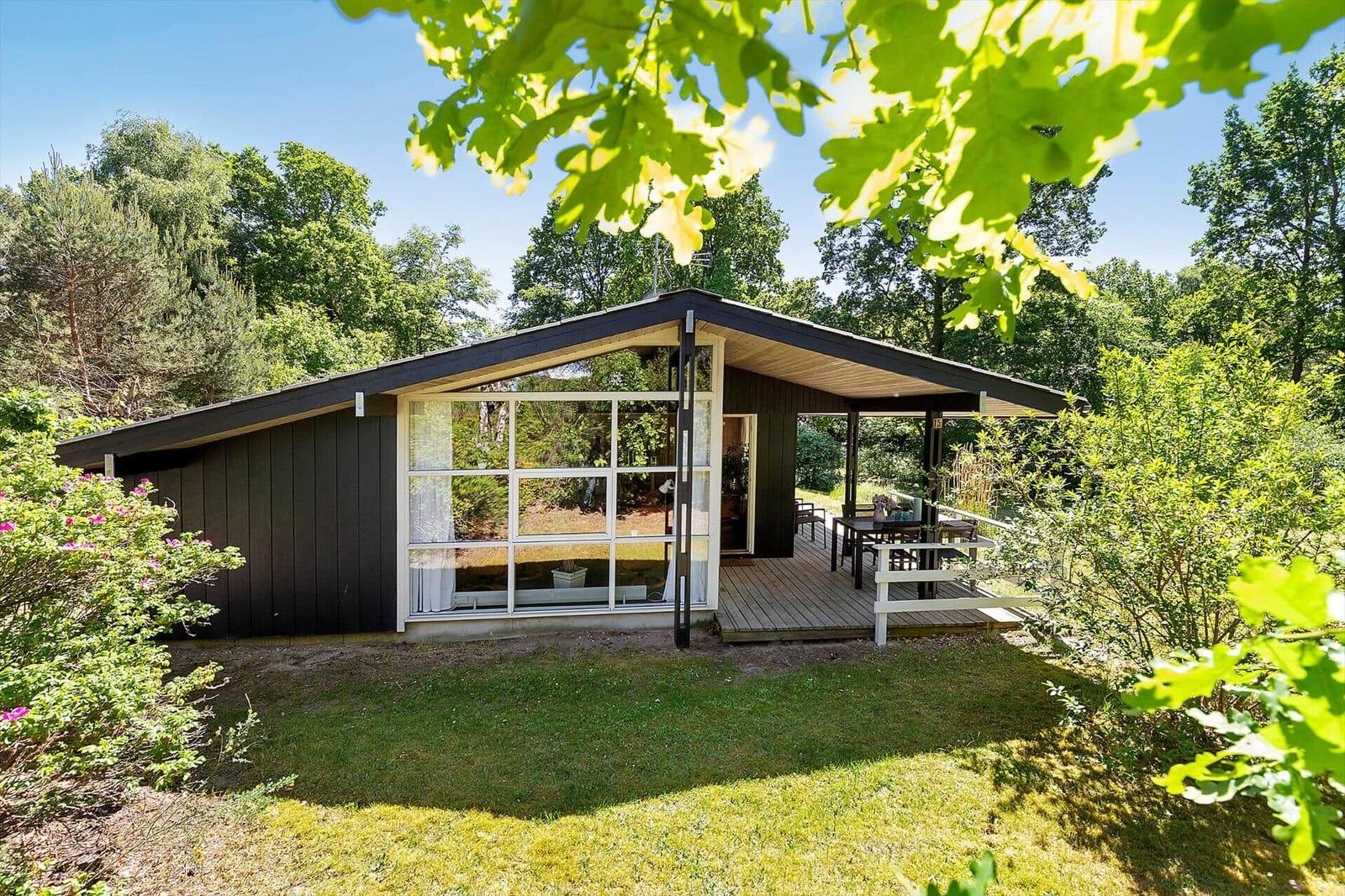 Modern wooden cabin with terrace and large window in the woods