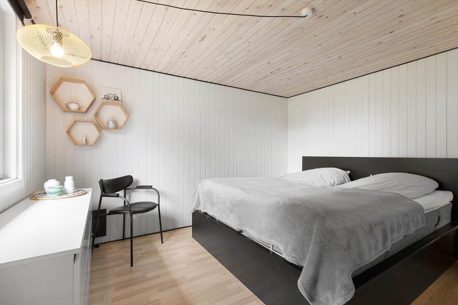 Schlafzimmer mit Bett, Schreibtisch und Hexagonregalen an der Wand.