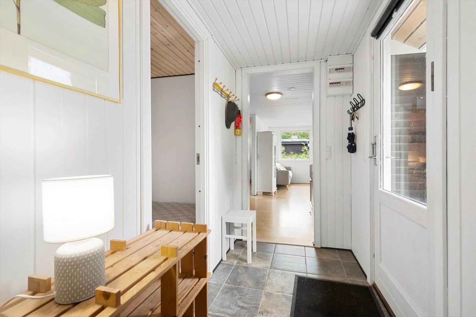 Hausgang mit Holzbank, Lampen und Blick in Wohnbereich