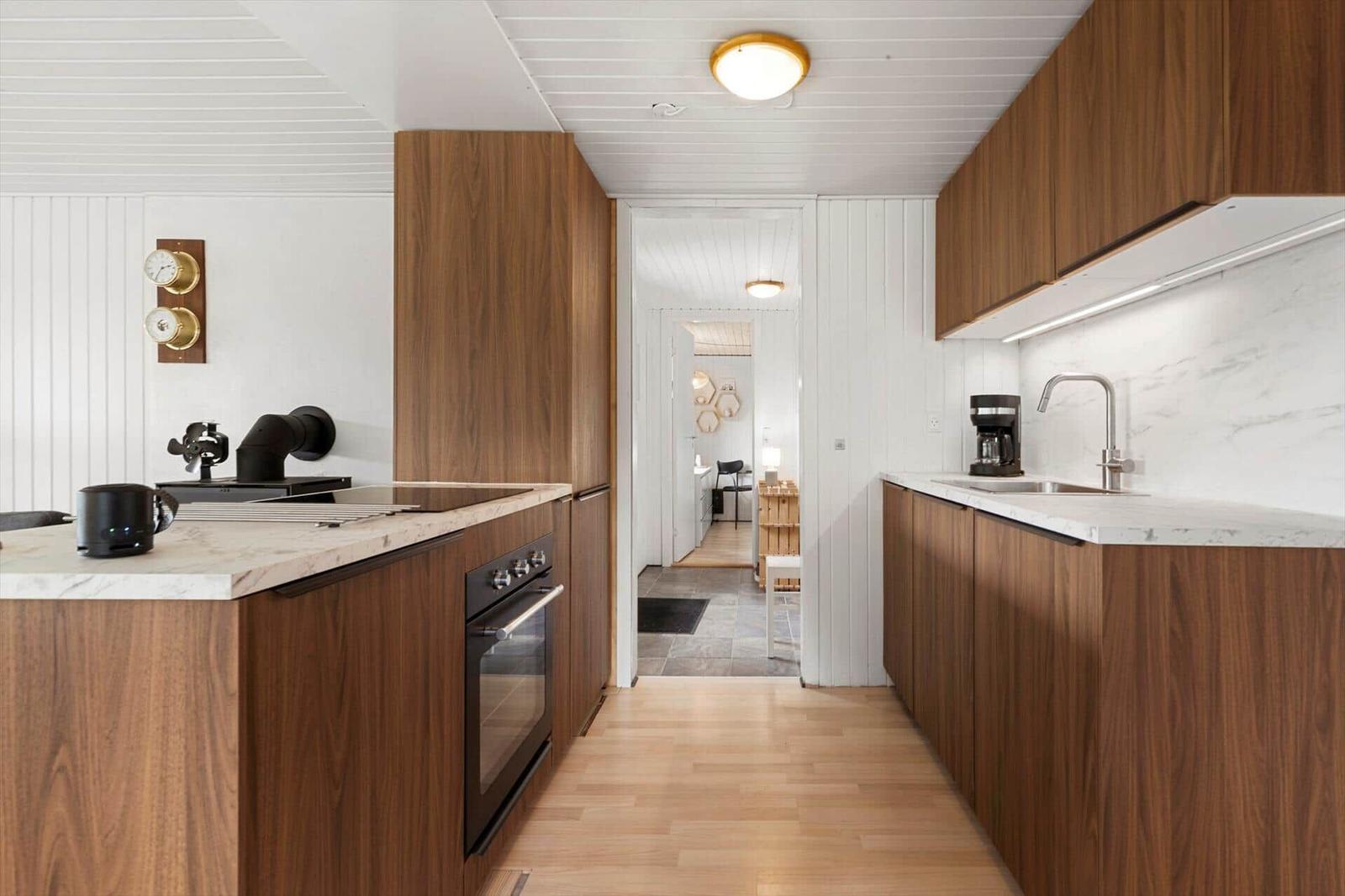Moderne Küche mit Holzschränken, Marmorarbeitsplatten und Blick in das Wohnzimmer.